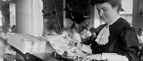 Employee numbering national banknotes with rotary numbering press.